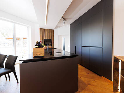Moderne Küche mit matt-grauer Oberfläche und ein, in die Wand eingebauter Hochschrank.