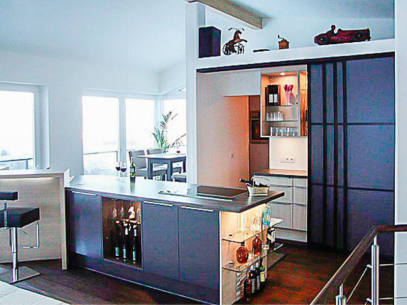 Wohnküche mit Schiebetür zur Speis und Kochinsel mit integrierter Bar-Lösung.