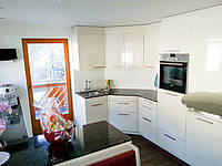 Weiße Küche die voll in den Raum integriert wurde mit einer Naturstein-Arbeitsplatte.