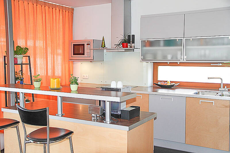 Küche mit kleiner Kochinsel und integrierter Bar-Lösung und Essplatz.