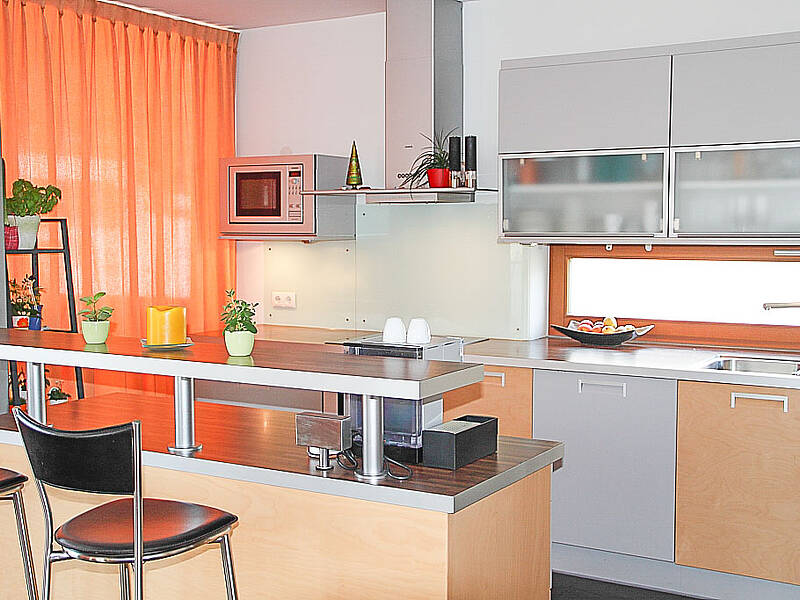 Küche mit kleiner Kochinsel und integrierter Bar-Lösung und Essplatz.