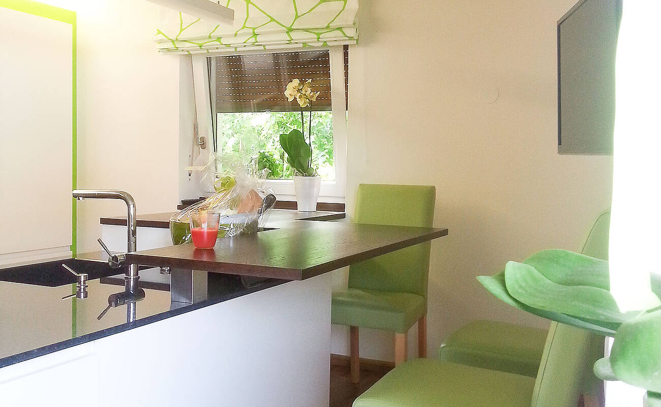 Küchenzeile mit Kochinsel und integrierter Sitzplatz-Lösung. Besonderheit ist die Bar-Lösung wo auch die edlen Tropfen ihren Platz finden.