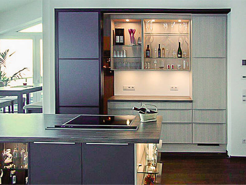 Wohnküche mit Schiebetür zur Speis und Kochinsel mit integrierter Bar-Lösung.