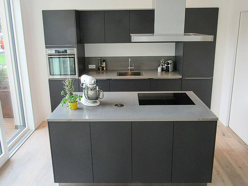 Küchenzeile in grau mit Kochinsel und Beton-Arbeitsplatte.