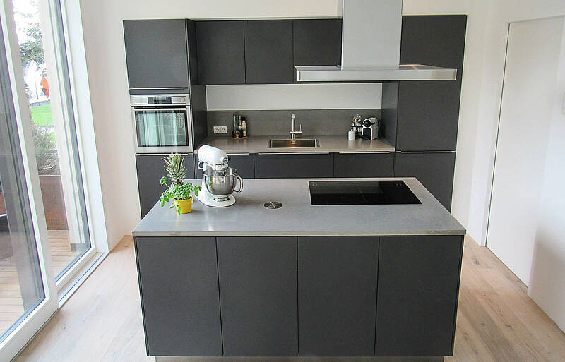 Küchenzeile in grau mit Kochinsel und Beton-Arbeitsplatte.