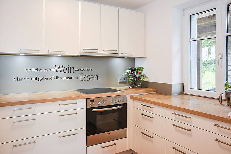 Vollintegrierte Küche in U-Form und Naturholz-Optik mit weißen Fronten.