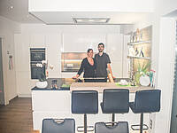 Küche in schwarz/weiß mit schönen optischen Akzenten in Holz und mit einer Bar-Lösung.