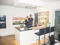 Küche in schwarz/weiß mit schönen optischen Akzenten in Holz und mit einer Bar-Lösung.