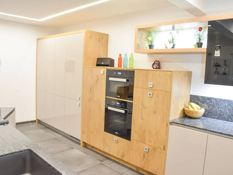 Moderne U-Küchen in Holz-Optik und mit Naturstein-Arbeitsplatte.