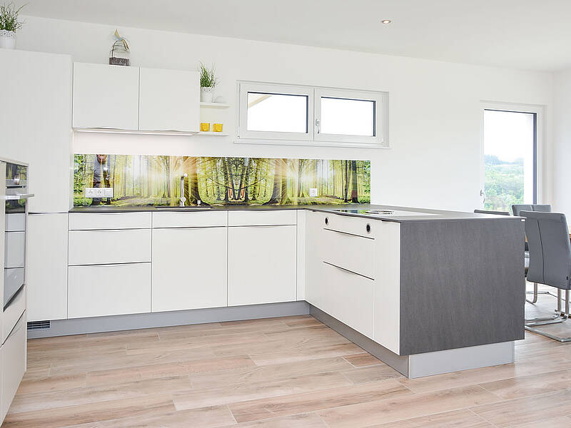 L-Küche mit getrennter Gerätefront, bedruckter Glasrückwand und einer Essplatz-Lösung.