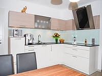 L-Küche mit Holz-Optik bei den Oberschränken und einer Glasrückwand.
