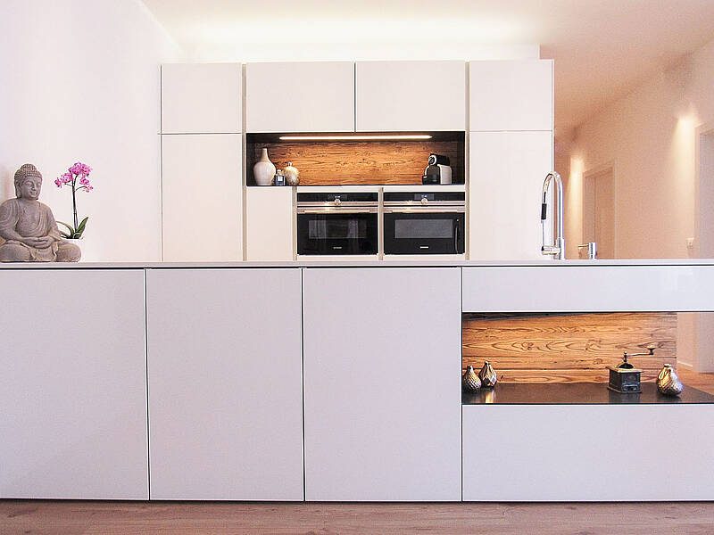 Küchenzeile in weiß mit Kochinsel und Vertiefungen im Holzdesign.
