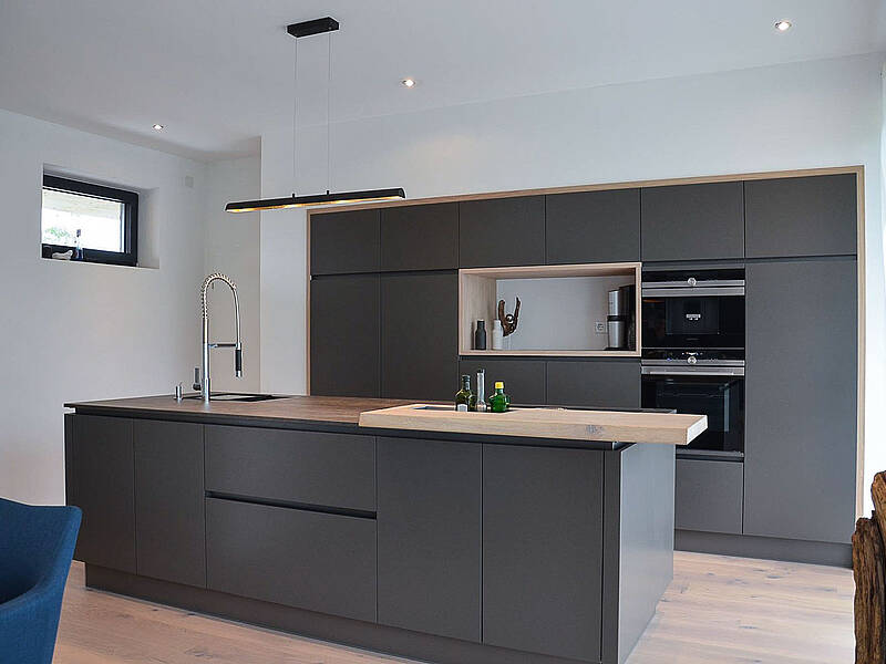 Küche in grau und integrierter Bar-Lösung aus Holz.