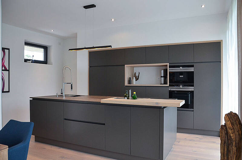 Küche in grau und integrierter Bar-Lösung aus Holz.