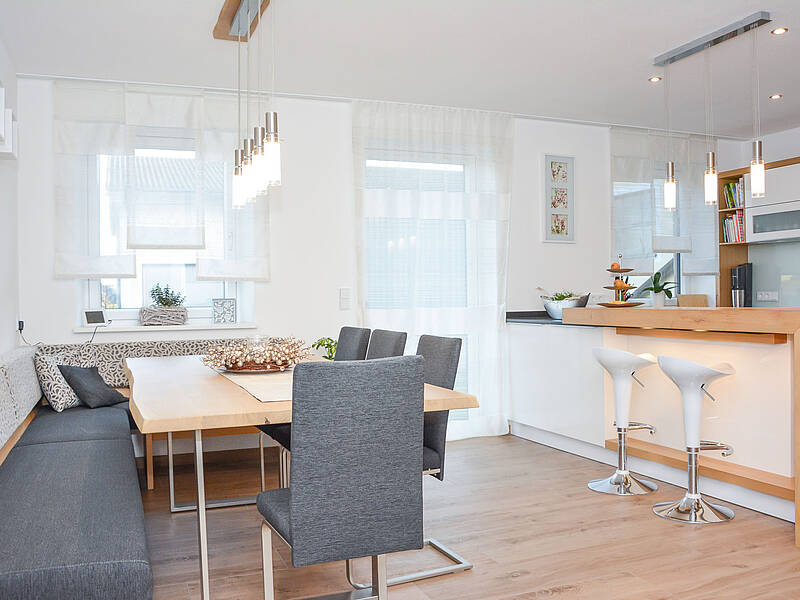U-Küche in weiß und Holz-Optik mit integrierter Barlösung und einem schönen Essplatz.