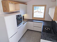 U-Küche in weiß mit Holz-Optik und Naturstein-Arbeitsplatte.