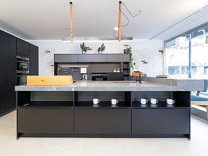 Küche in schwarz mit Kochinsel und integrierter Barlösung