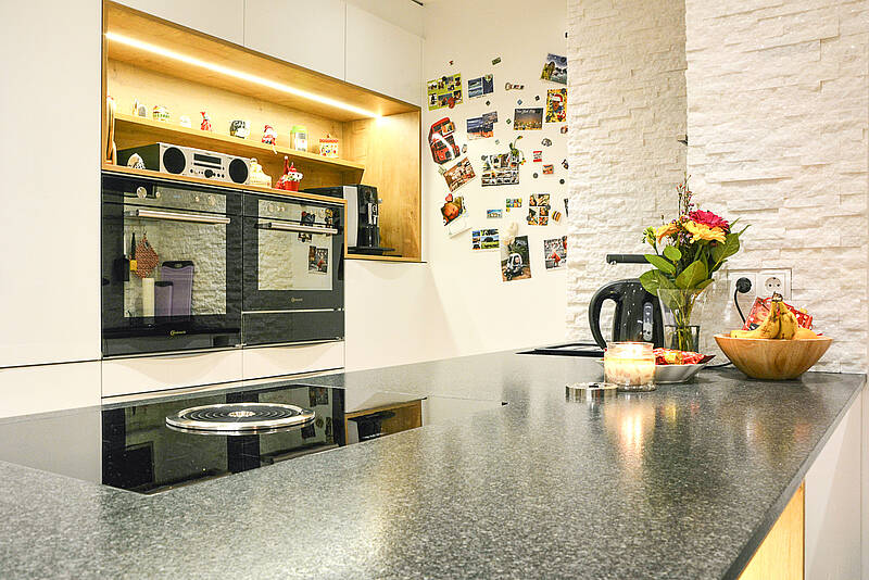 Moderne Küche mit Kochinsel und Naturstein-Arbeitsplatte und die E-Geräte in der richtigen Arbeitshöhe.