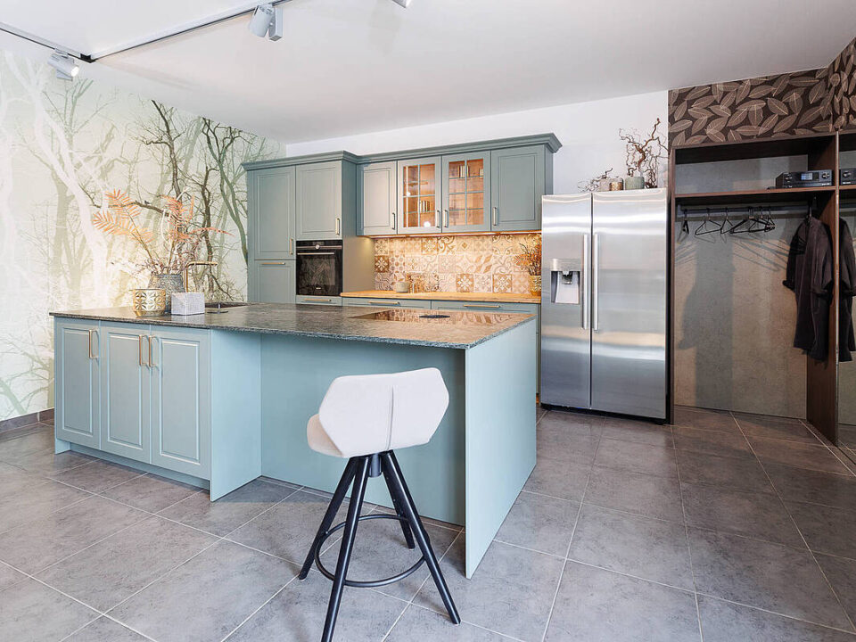 Landhausküche mit mintfarbigen Fronten und heller Natursteinarbeitsplatte