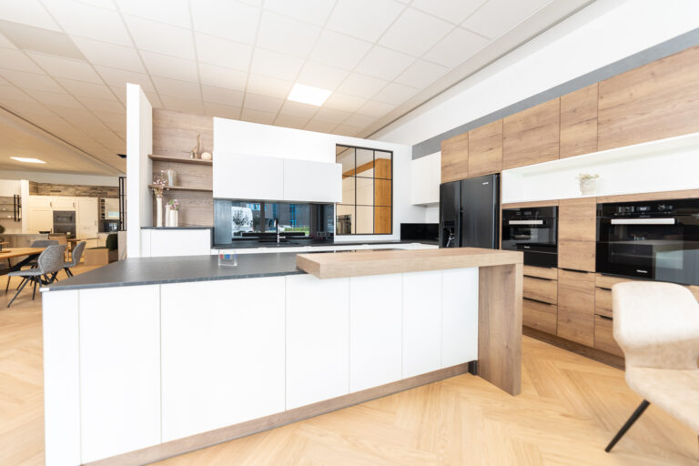 Moderne olina Küche in weiß Holzkombination. Thekenaufsatz auf Insel mit schwarzer Natursteinarbeitsplatte