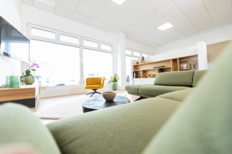 Wohnzimmersituation mit grüner Polstercouch und gelben Drehstuhl