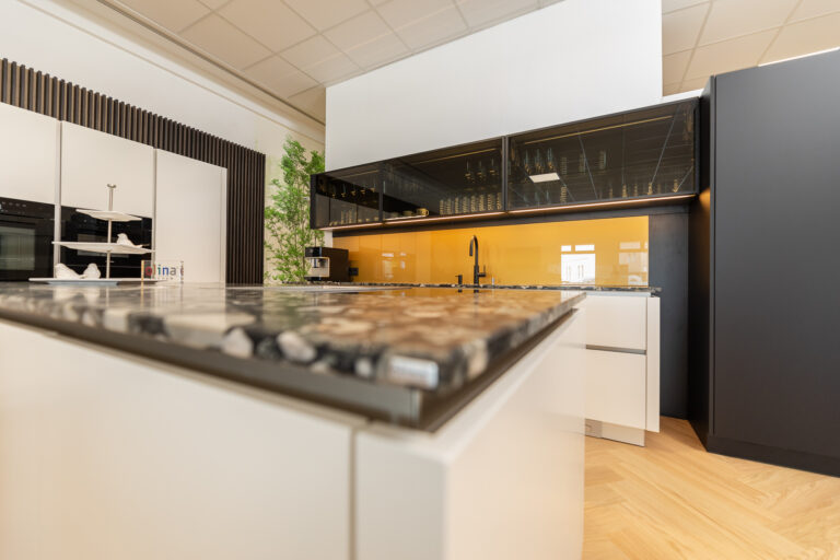 Küche mit weißer Front in matt mit gelber Glasrückwand und Natursteinarbeitsplatte in dunkel