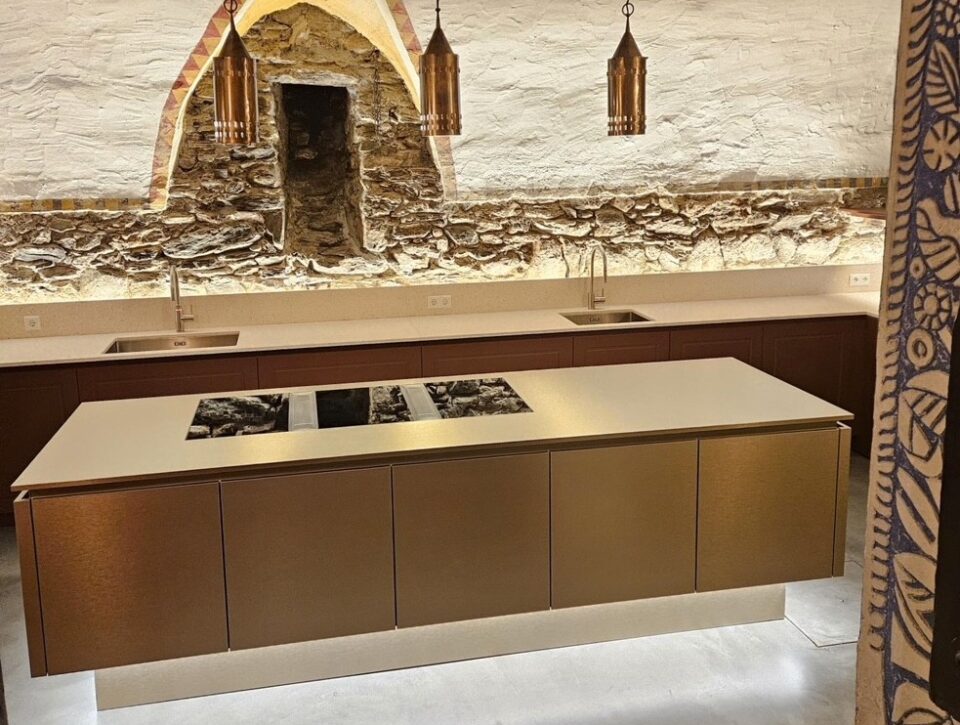 Küche mit Front in gold und heller Mineralstoffarbeitsplatte