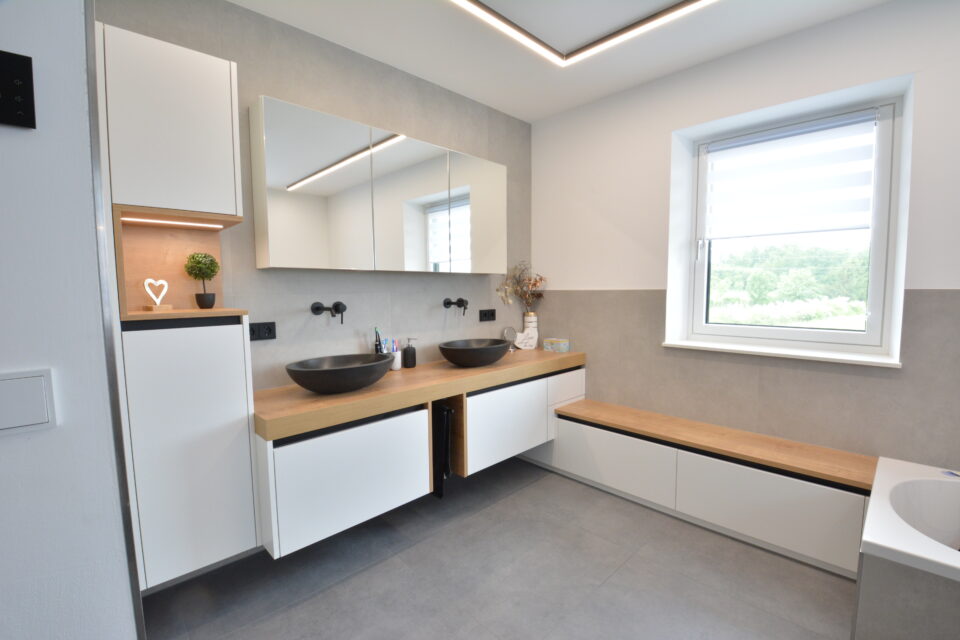 Badezimmerverbau in weiß mit Naturholz in Eiche, mit zwei schwarzen Aufsatzwaschbecken rund